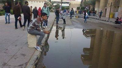 طالب يصيد سمك في بركة مياه الامطار بجامعة حلوان
