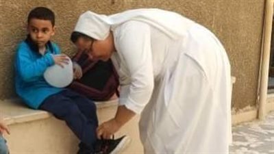 مديرة مدرسة الراهبات الابتدائية المشتركة بإسنا تربط حذاء تلميذ