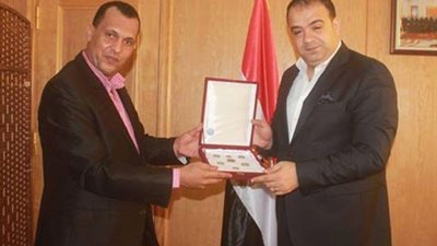 بالصور.. معلم لغة فرنسية يهدى محافظ الفيوم عملات وطنية تذكارية